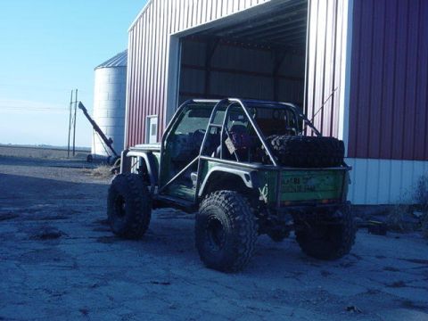 1992 Ford Bronco - Custom off-road SUV with extensive roll cage and spare tire mounted at rear.