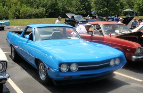 1976 Ford Ranchero - A bright blue coupe utility vehicle is parked at an outdoor event, with other vehicles visible in the background.