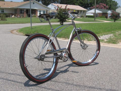 1994 Ford Bronco - A custom bicycle with a chrome frame and red-striped tires is parked on a suburban street.