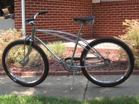 1994 Ford Bronco - A shiny chrome cruiser bicycle with distinctive red-lined tires is parked on a sidewalk in front of a brick building.