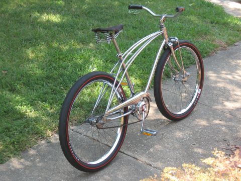 1994 Ford Bronco - A vintage-style bicycle with a chrome frame and red-lined tires sits on a paved path next to a grassy area.