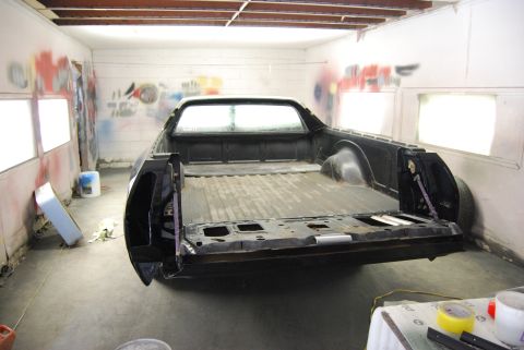 1975 Ford Ranchero - A black Ford Ranchero is parked in a workshop, viewed from the rear with its tailgate down.
