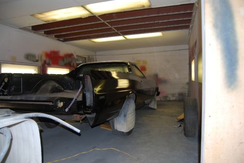 1975 Ford Ranchero - Black 1975 Ford Ranchero in a paint booth, rear quarter view. The vehicle is undergoing restoration work.