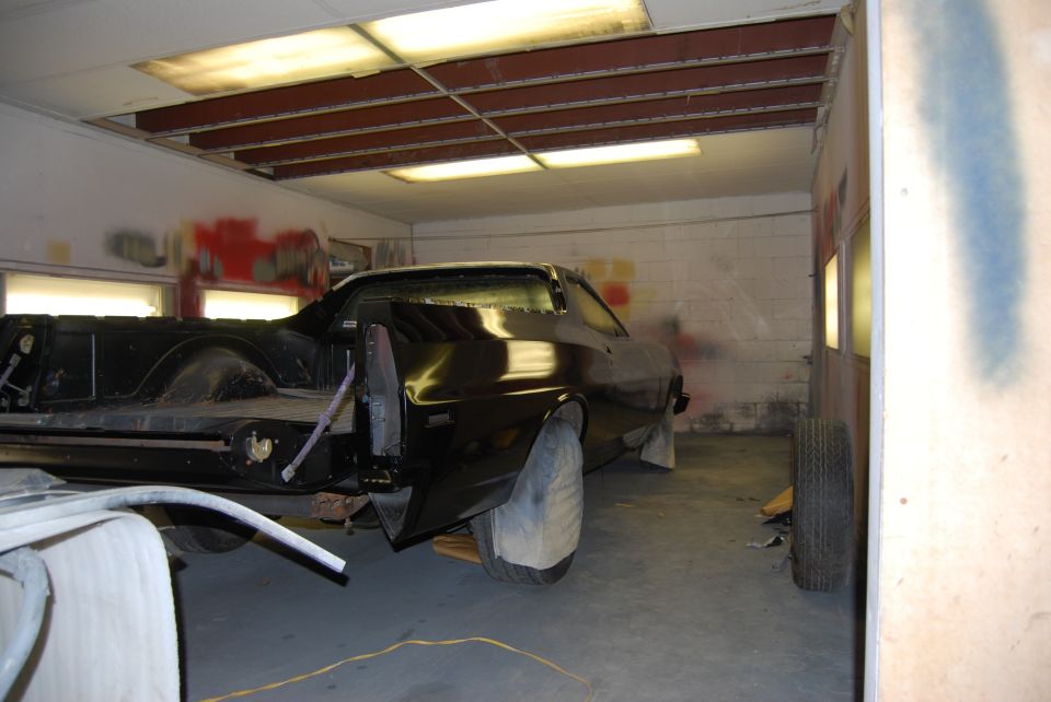 1975 Ford Ranchero in a paint booth, rear view. Body is black, appears to be undergoing restoration