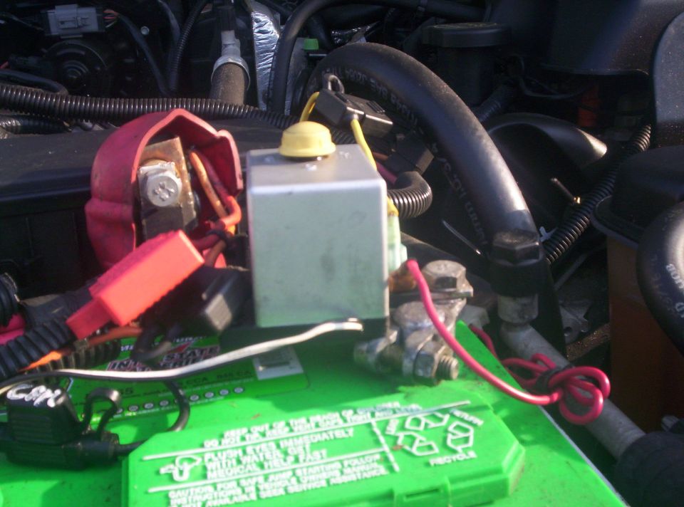 Green Interstate battery with silver relay box and red positive cables in engine bay