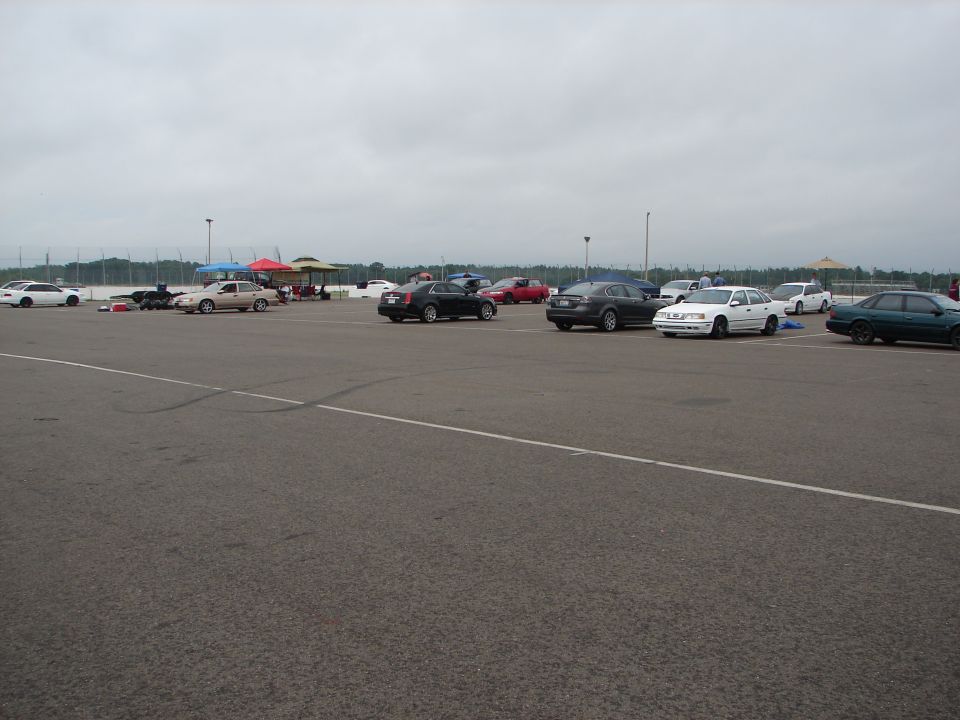Parking lot scene with various cars under a cloudy sky