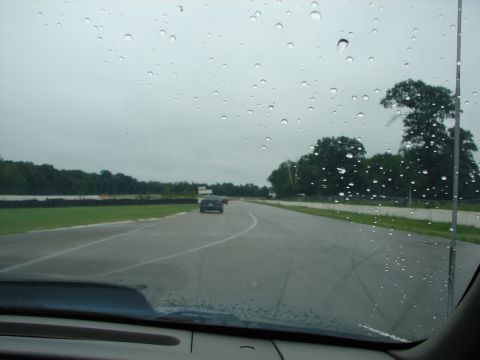 1992 Ford Taurus - Raindrops on the windshield obscure the view of cars driving on a wet racetrack.