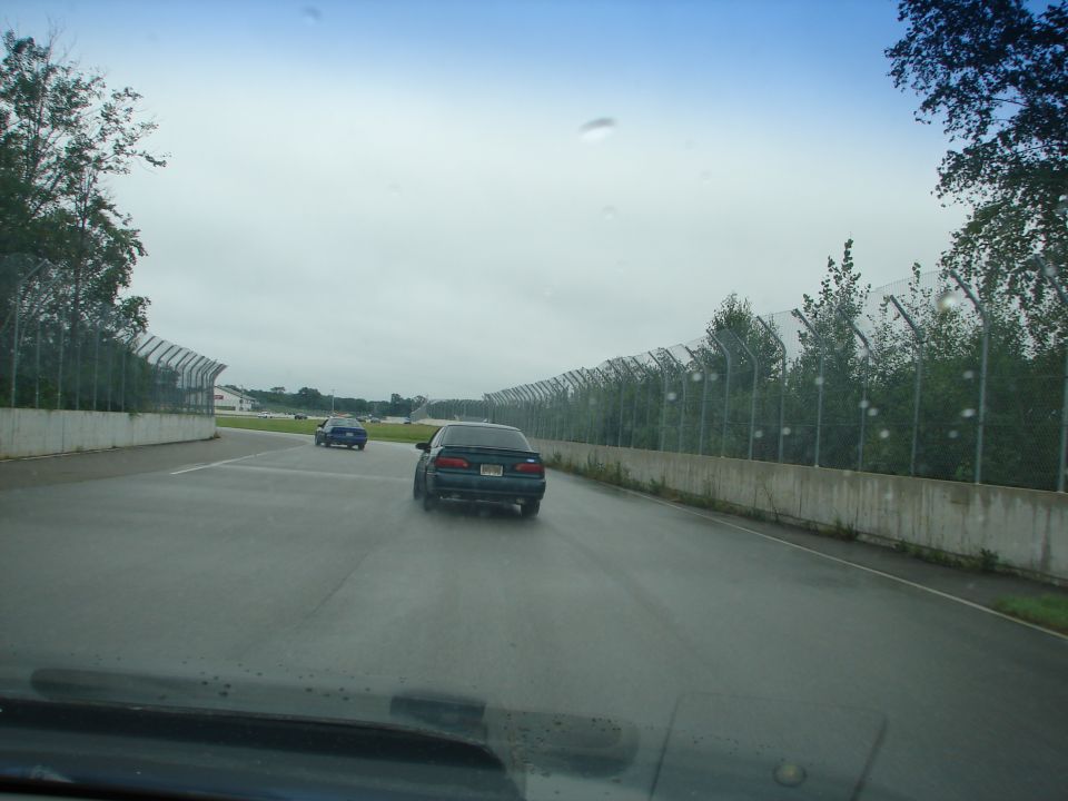 two cars driving on a wet track, one in front of the other