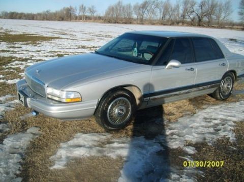 2000 Mercury Grand Marquis - A silver sedan sits in a field with patches of snow and dry grass under a clear sky.