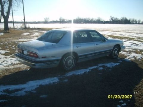 2000 Mercury Grand Marquis - Silver sedan with chrome trim parked on dirt and snow, rear view.