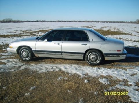 2000 Mercury Grand Marquis - A silver sedan sits in a field with patches of snow and dry grass under a clear blue sky.