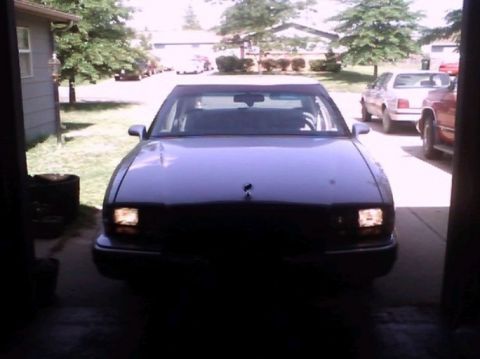 2000 Mercury Grand Marquis - A dark sedan is parked in a garage, with other vehicles visible in the background.