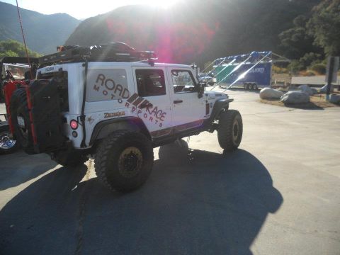 1986 Ford Bronco - Modified white Jeep Wrangler with off-road tires and roof rack is parked outdoors.