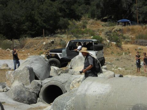1986 Ford Bronco - Off-road vehicle tackles a challenging obstacle course with large rocks and concrete pipes.