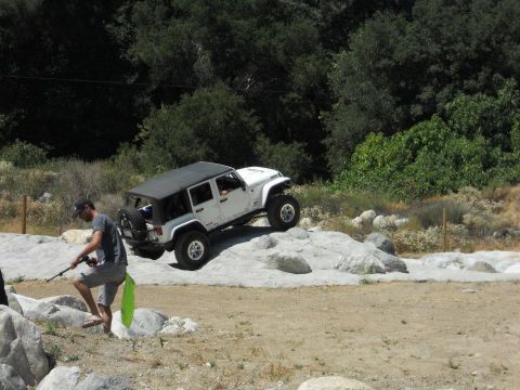 1986 Ford Bronco - A white Jeep Wrangler navigates a rocky trail in a natural setting.