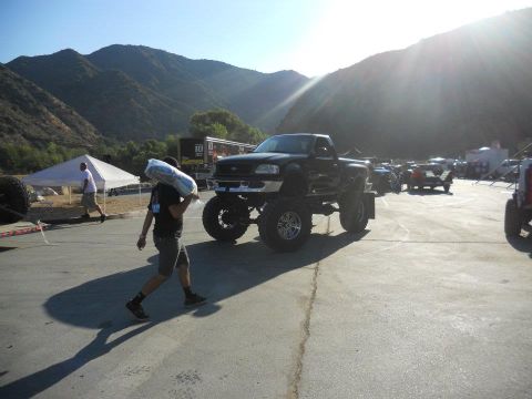 1986 Ford Bronco - A lifted black pickup truck is parked outdoors with mountains in the background.