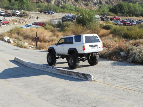 1986 Ford Bronco - A heavily modified Toyota 4Runner navigates an off-road park with other vehicles present.