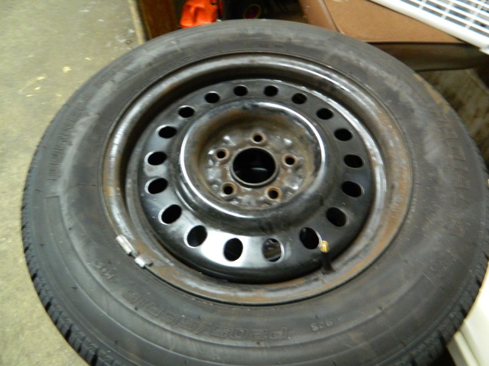 Tire and black steel wheel with multiple holes, viewed from the front