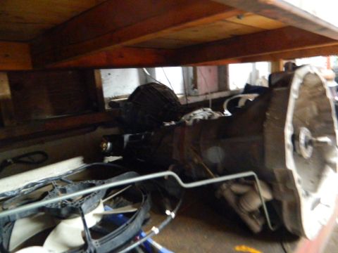 1995 Honda Civic - Transmission assembly and cooling fan parts are stored under wooden shelving.