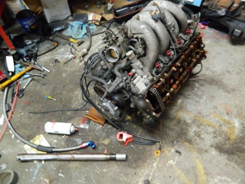 1995 Honda Civic - An engine sits on the floor, surrounded by tools and various automotive parts, suggesting a repair or rebuild process.