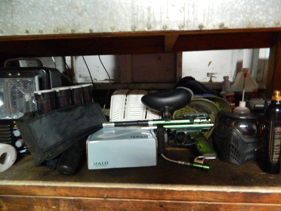 Paintball gun, mask, and loader box on a shelf