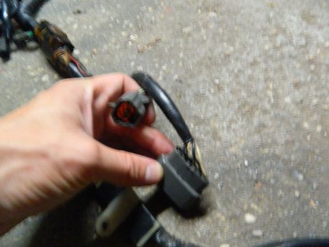 1995 Honda Civic - Close-up of a hand holding a wiring harness connector, with the background showing a concrete surface.