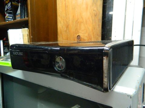 1995 Honda Civic - A black Xbox 360 console is shown on a shelf, with a wooden panel behind it.