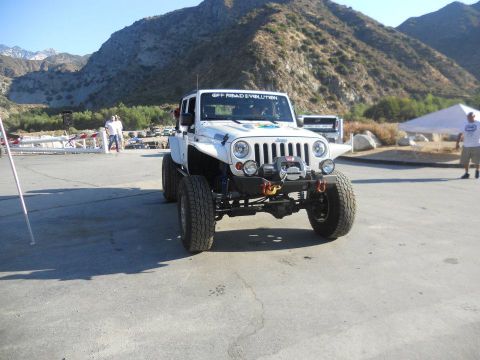 1986 Ford Bronco - Modified Jeep Wrangler with large tires and winch, seen in an outdoor setting with mountainous terrain.