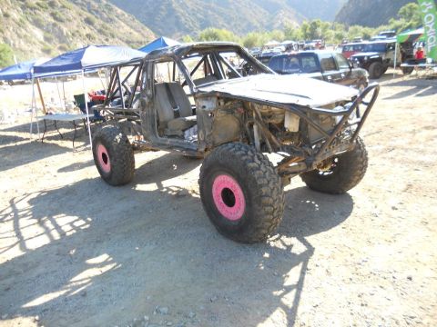 1986 Ford Bronco - This heavily modified off-road buggy features a custom roll cage and distinctive pink accents on its wheels.