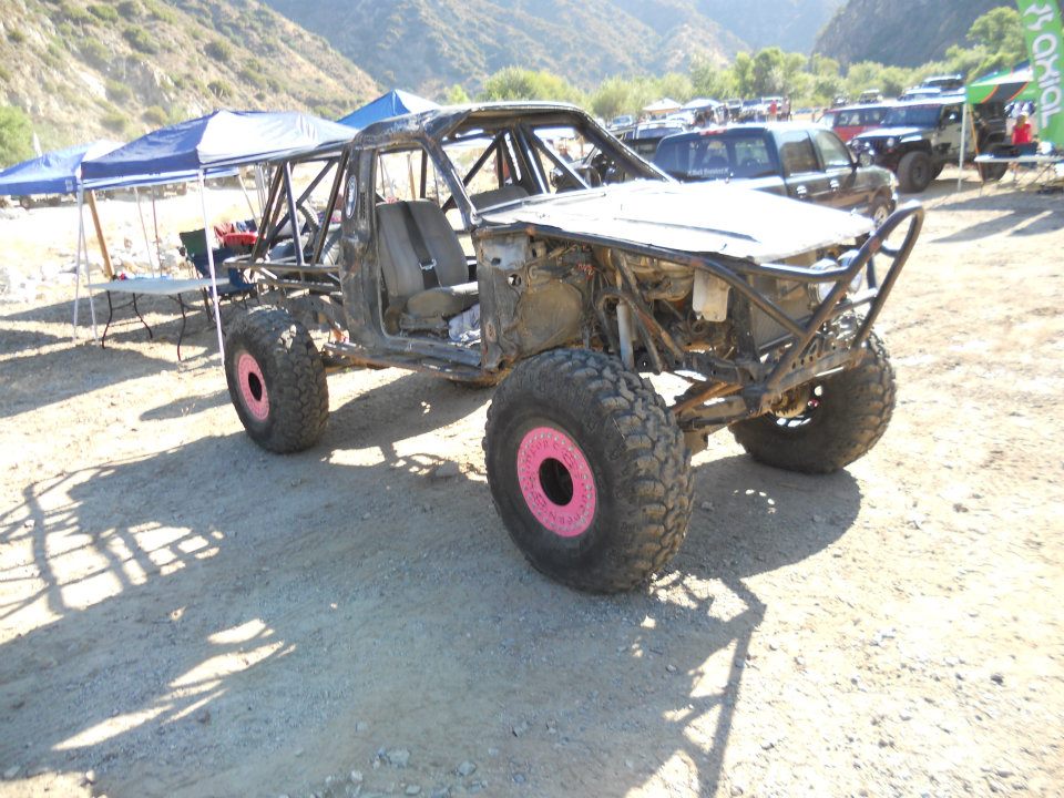 Off-road buggy with roll cage and pink wheel accents, front view