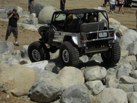 1986 Ford Bronco - A modified Jeep Wrangler tackles a challenging obstacle course with large rocks.