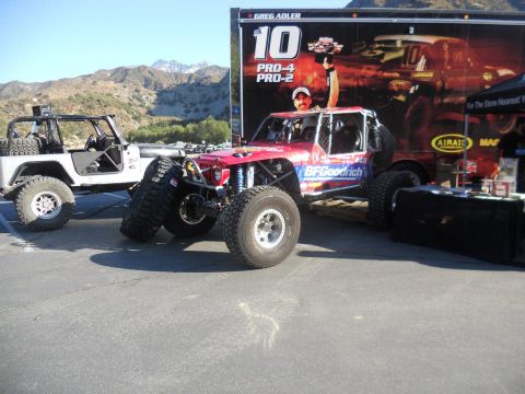 1986 Ford Bronco - Custom off-road trucks are displayed in front of a race trailer.