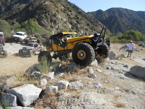 1986 Ford Bronco - A group of off-road vehicles navigate a rocky trail in a mountainous area.