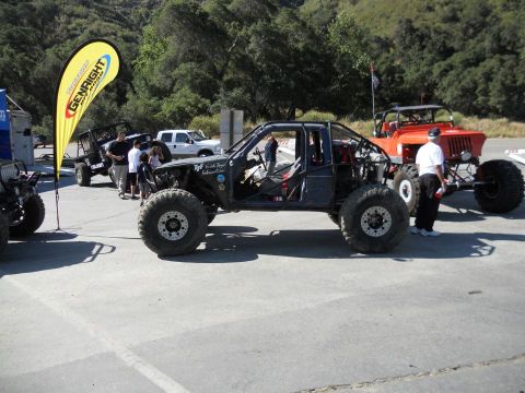1986 Ford Bronco - Multiple custom off-road vehicles are gathered outdoors, with one prominently displayed in the foreground.