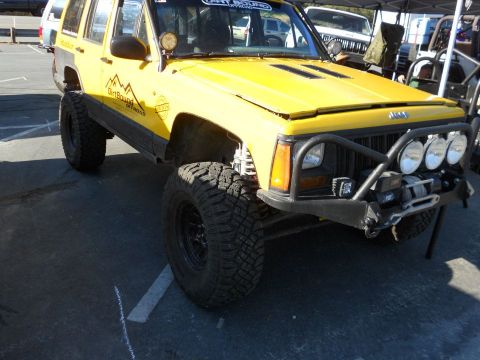 1986 Ford Bronco - This modified Jeep Cherokee XJ features off-road enhancements, including aggressive tires and a custom bumper with auxiliary lights and a w…