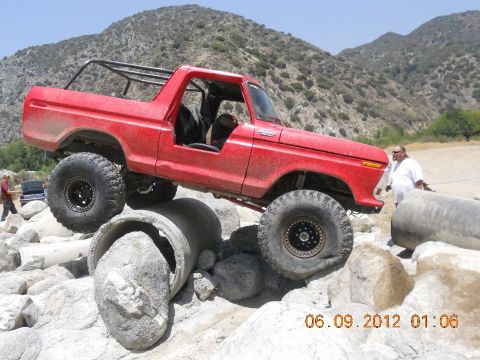 1986 Ford Bronco - A red Bronco navigates a rocky obstacle course with large tires and a roll cage.