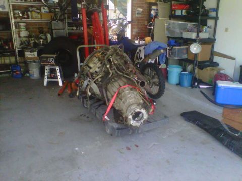 1994 Ford Bronco - Engine and transmission assembly is the main subject, with a motorcycle in the background.