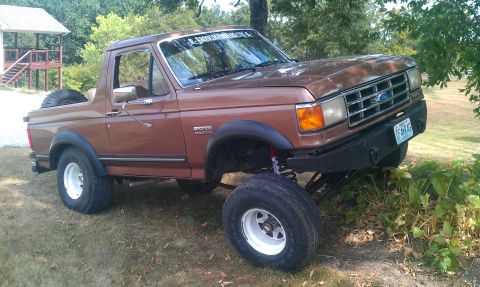 1987 Ford Bronco - Modified 1987 Ford Bronco with off-road tires and suspension, parked outdoors.