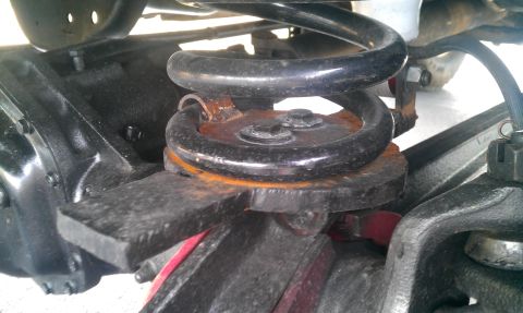 1987 Ford Bronco - Detail of the suspension system, focusing on the coil spring and surrounding axle components.
