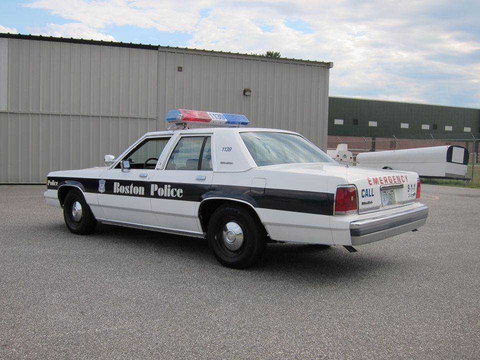 White 1991 Ford Crown Victoria LTD police car with black stripe and 'Boston Police' text, parked on asphalt