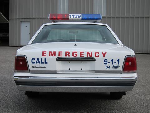1991 Ford LTD Crown Victoria - Rear view of a white 1991 Ford Crown Victoria LTD police car, emergency lights and markings.