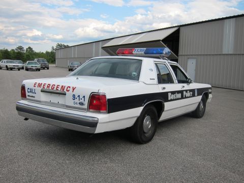 1991 Ford LTD Crown Victoria - Boston Police car, a 1991 Ford Crown Victoria LTD, parked outside a building with other vehicles in the background.