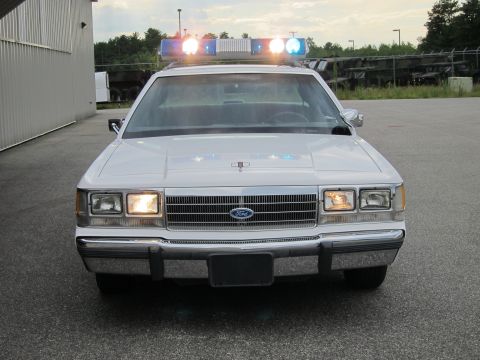 1991 Ford LTD Crown Victoria - Front view of a white 1991 Ford Crown Victoria LTD police car with its light bar illuminated.