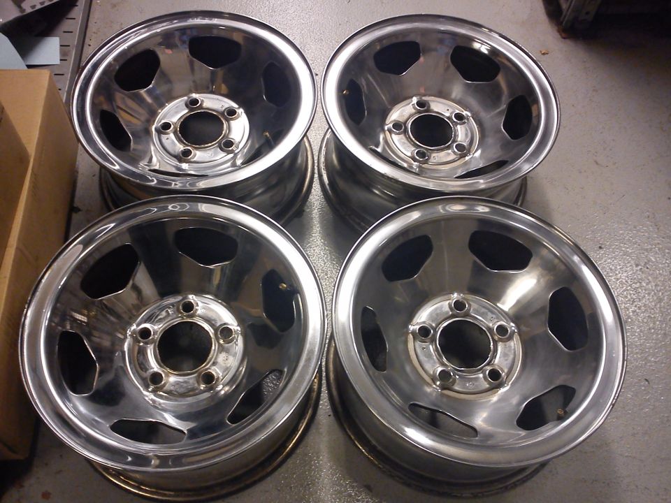 Four chrome wheels with five lug holes and a hexagonal center cap area