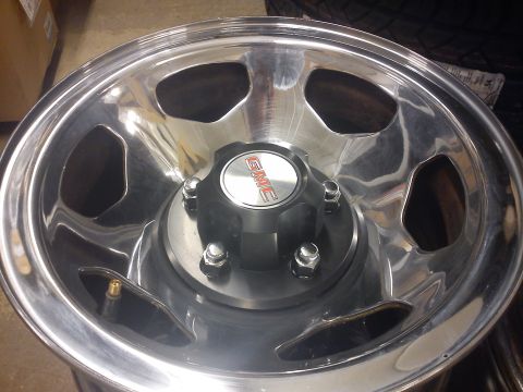 1997 Chevrolet Silverado 1500 - A close-up view of a polished aluminum GMC wheel, showing its five lug nuts and center cap.