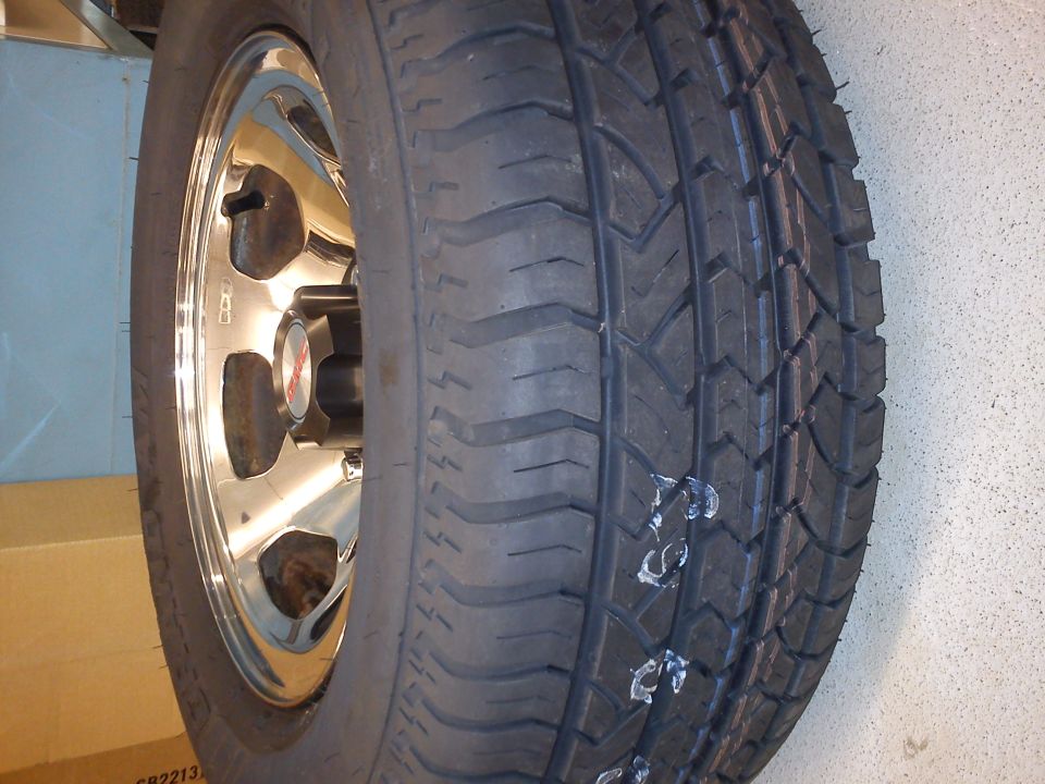 Close-up of a tire on a chrome wheel. Some white markings are on the tire tread