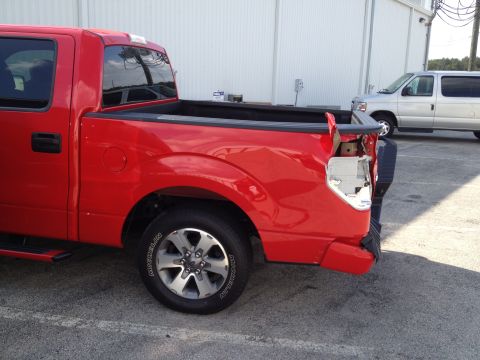 2006 Ford F-350 - This red pickup truck has significant damage to its rear end, including a missing taillight and bent bumper.