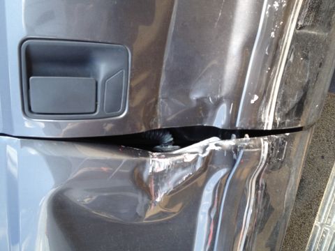 2006 Ford F-350 - The rear bumper of a dark gray truck shows extensive damage from an impact.