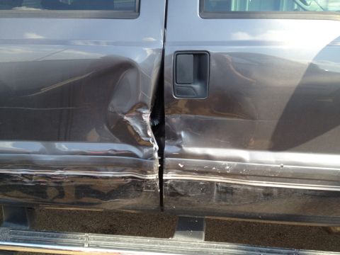 2006 Ford F-350 - The doors of this 2006 Ford F-350 show severe damage, with the driver's side rear door heavily impacted.