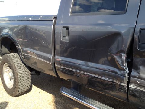 2006 Ford F-350 - Rear quarter panel and door of a 2006 Ford F-350 show extensive damage.